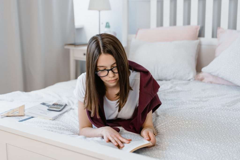 Girl reading a poetry book on her bed