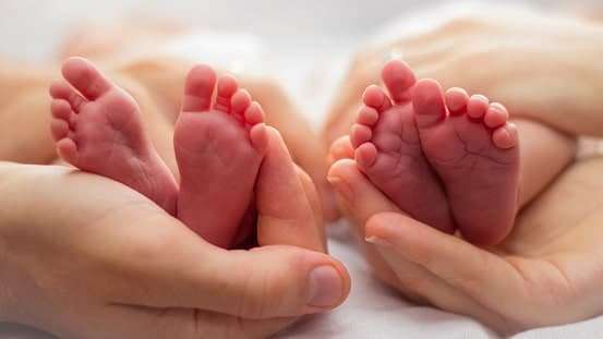 Twin babies feet in mother hand